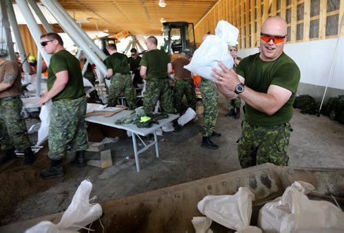 Captian Jerry Larkin, one of the soldiers from CFB Shilo, who along with workers from the Municipality of Portage la Prairie work to make sandbags at the Portage Yard, Saturday, July 5, 2014. (TREVOR HAGAN/WINNIPEG FREE PRESS)