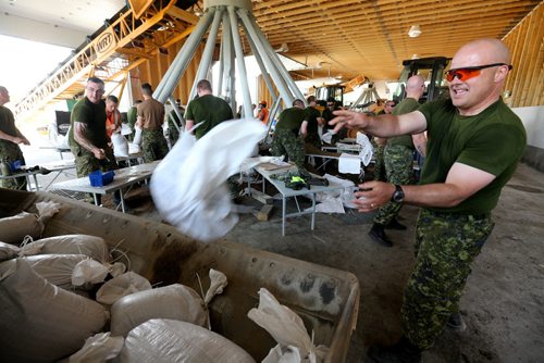 Captian Jerry Larkin, one of the soldiers from CFB Shilo, who along with workers from the Municipality of Portage la Prairie work to make sandbags at the Portage Yard, Saturday, July 5, 2014. (TREVOR HAGAN/WINNIPEG FREE PRESS)