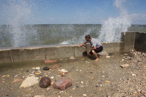 Adam Dalman ducks as water slams against the concrete foundation of his neighbors cottage that was destroyed in 2011. 140706 - Sunday, July 06, 2014 -  (MIKE DEAL / WINNIPEG FREE PRESS)