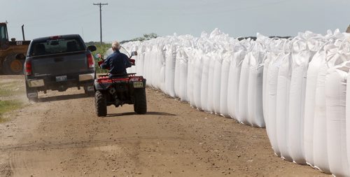 Residents drive alongside super sand bags at the East end of Delta Beach Monday as protection of the road in case of a required flood evacuation- The west side of Delta Beach has been evacuated yesterday- See Adam Wazny story- July 07, 2014   (JOE BRYKSA / WINNIPEG FREE PRESS)