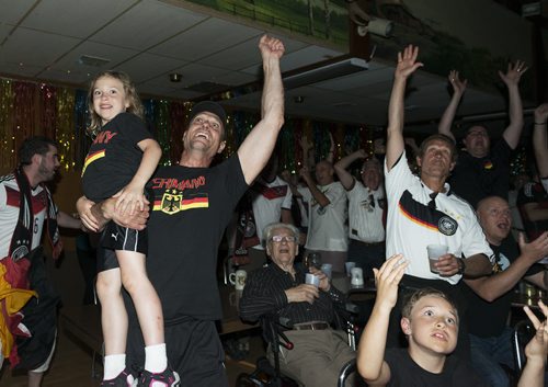 Holding his daughter, Chanel, in his arms, Robert Schulz cheers with his brother, Ric (front in white shirt, with son, Robbie, below) in the German Society of Winnipeg 
clubhouse as Germany scores five goals in the first 30 minutes of its game against Brazil Tuesday.
 Sarah Taylor / Winnipeg Free Press July 8th, 2014