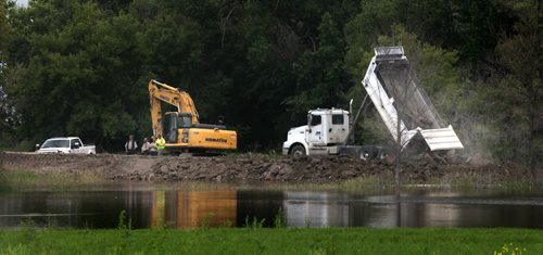 Earth movers and trucks fill in a gap on the Assinaboine River Dike near St Eustashe. See story. July 8, 2014 - (Phil Hossack / Winnipeg Free Press)