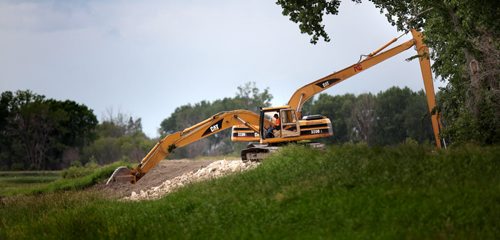Heavy equipment operators move rip-rap to reinforce a section on the Assinaboine River Dike between St Eustashe and Portage la Prairie. See story. July 8, 2014 - (Phil Hossack / Winnipeg Free Press)