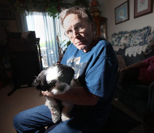 Hepatitis C patient Robert Walker poses in his St Vital apartment holding  "Sparky" his "unconditional constant companion". The pet pooch stayed at his side through all his chemotherapy and other treatment for the past few years. See Larry Kusch story. July 9, 2014 - (Phil Hossack / Winnipeg Free Press)