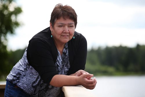Linda Redsky a resident of Shoal Lake 40 First Nation  looks into the clear water at the edge of her home where she went through the ice and almost drowned while fetching water in the winter.  The community held  an event Wednesday marking the 100th anniversary for the flooding of their land to provide water for the City of Winnipeg.  The flood disconnects them from the mainland except for a barge that runs in the summer and  a temporary bridge via a winter road in the winter.  See Mary Agnes story. July 09, 2014 Ruth Bonneville / Winnipeg Free Press