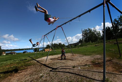 Children play on a set of swings near the docks of Shoal Lake 40 First Nation Wednesday just before government officials and dignitaries arrive to their manmade island marking the 100th anniversary for the flooding of their land to provide water for the City of Winnipeg.   The flood disconnected them from the mainland except for a barge that runs in the summer and  a temporary bridge via a winter road in the winter.  See Mary Agnes story. July 09, 2014 Ruth Bonneville / Winnipeg Free Press