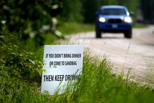 An "out of the neighborhood truck" drives past as sign erected by Laurie Wolfe and her husband Brian who are sick of all the look-e-loos driving past their St.Francois Xavier home to see flood preparations. They have made a sign asking people not there to help to keep on moving. See Gord Sinclair's story. July 10, 2014 - (Phil Hossack / Winnipeg Free Press)