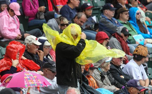 A fan tries to get his poncho on as the rain starts to fall during the second inning of the Winnipeg Goldeyes game against the Gary Southshore Railcats Sunday afternoon at Shaw Park. 140713 - Sunday, July 13, 2014 -  (MIKE DEAL / WINNIPEG FREE PRESS)