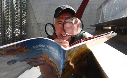 Winnipeg Fringe Festival Executive Producer --  Chuck McEwen hams it up for the camera as he examines this year's program (We like it when you Watch) at the Festival's MainStage in Old Market Square.   July 15, 2014 Ruth Bonneville / Winnipeg Free Press
