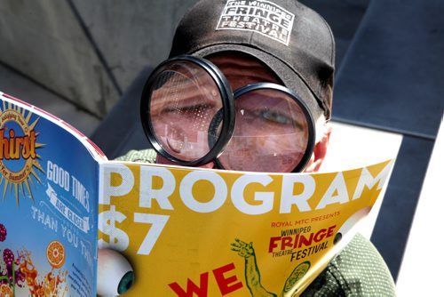 Winnipeg Fringe Festival Executive Producer -- Chuck McEwen hams it up for the camera as he examines this year's program (We like it when you Watch) at the Festival's MainStage in Old Market Square.   July 15, 2014 Ruth Bonneville / Winnipeg Free Press
