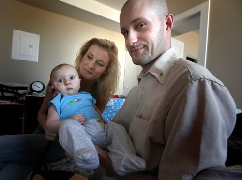 Ernest Dlutek and his wife Justyna came to Canada in April 2013 on a one-year work visa. THey're posing here in their tiny north main apartment with son Antony who was born here five months ago with severe heart defect and has been flown to Edmonton for baby cardiac surgery twice - as recently as June. Now the Canadian  government is telling them their work visa has expired and they have to go back to Poland. Their doctor says the baby needs to stay and receive proper care and this couple who speaks English fluently and are both well-educated and eager to work are afraid  to go back to Poland with Antony who will need surgery again because there isnt proper care. See Carol Sanders story. July 15, 2014 - (Phil Hossack / Winnipeg Free Press)