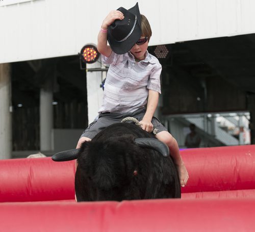Seven year old Tannet Treichel from Darlingford rides the mechanical bull at the Morris Stampede on Thursday. Sarah Taylor / Winnipeg Free Press July 17, 2014