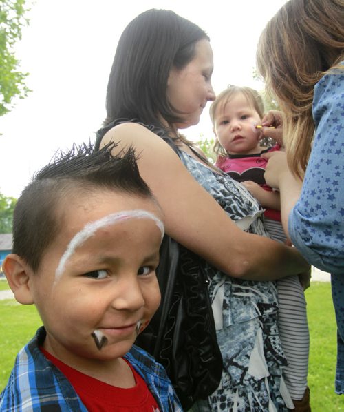At left, Keilan Dubuc,4, waits for his sister Anjalie,2, held by her mother Crystal  gets her face painted by Lindsay Giesbrecht at the North End Family Centre's 5th Annual Community free BBQ where about 800 people were served a meal Thursday at Machray Park. In a news release North End Family Centres Founder and Executive Director, Kyle Mason said Our Community BBQ is one of the many ways we are building a true sense of community in the North End of Winnipeg. When people gather for a meal, great memories are made and a strong and healthy community is built." Wayne Glowacki / Winnipeg Free Press July 24  2014