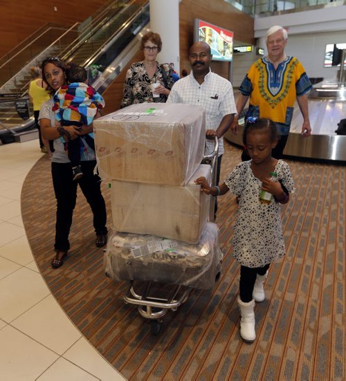 local - Hospitality House Refugee Ministry .LtorR an exhausted Semhar Solomon with her childre Yobel Efrem age 2 in arms  and ger daughter Right Diliat Hagos age 5  , met by  Karin Gordon (68)  and Hogos wheeling cart of luggage ,  and  Tom Denton (80) at the airport welcoming refugees sponsored through Hospitality House Refugee Ministry, which the two of them run.Äì newcomer arrivals  at the airport are joyful, raucous events Äì they usually have tons of long-lost family and friends greeting them.Carol Sanders | Reporter , Ä®July 24 2014 / KEN GIGLIOTTI / WINNIPEG FREE PRESS