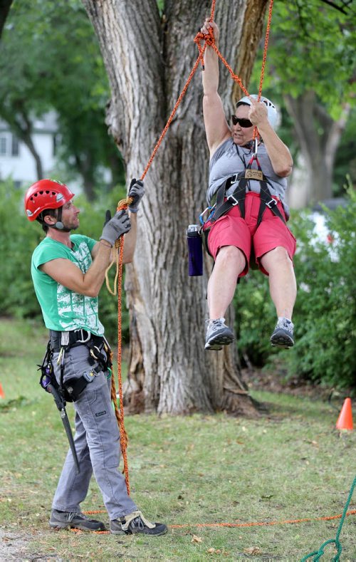 Chris Barkman, assisting Jocelyne Poirier. Barkman is  with Travel Roots, a Winnipeg adventure company that offers tree climbing excursions around the city, Saturday, July 26, 2014. (TREVOR HAGAN/WINNIPEG FREE PRESS) - for Dave Sanderson 49.8 piece.