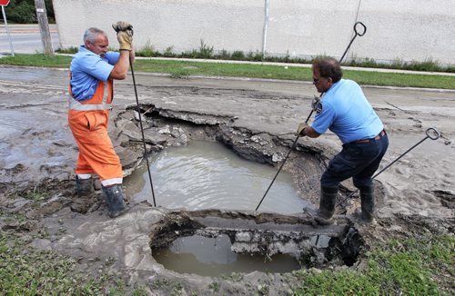 A City of Winnipeg crew works on finding a leak in the watermain that has created a sinkhole on Washington Avenue at Henderson Highway Sunday morning. About a block of houses are without water until the main can get fixed.  140727 July 27, 2014 Mike Deal / Winnipeg Free Press