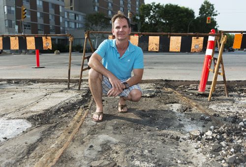Streetcar historian Steven Stothers sits at Portage Avenue and Sherbrook Street where old streetcar rails from 1955 were dug up during a construction project. Stothers wishes Winnipeg would reconsider using streetcars on its roads. Sarah Taylor / Winnipeg Free Press July 30, 2014