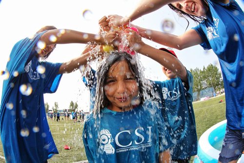 Harmony, 7, from the West Grove Community School Investigators Summer Learning Program gets "sponged" by her councillors during a water fight Thursday morning as almost 1000 kids in the CSI program gathered at the Waverley Soccer Complex for the first Jumpstart Games.  140731 July 31, 2014 Mike Deal / Winnipeg Free Press