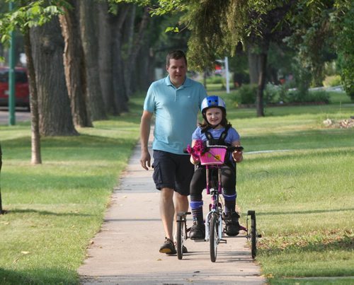 10 yr old Waverley Leduc  with her special needs specially designed custom bike made by a Winnipeg manufacturer rides it in front of her River Heights home with her father Jamie giving chase.  See Adam Wazny story- July 31, 2014   (JOE BRYKSA / WINNIPEG FREE PRESS)