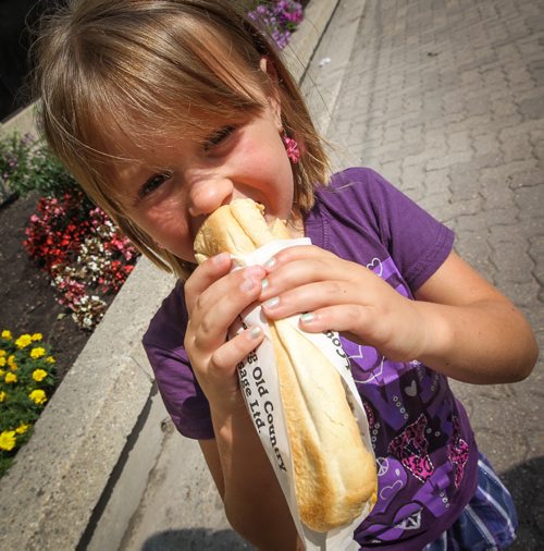 Ainslie Zubec, 6, eats a hot dog for lunch, a family tradition in the Zubec family. Crowds gather during the noon hour for lunch on Broadway Tuesday. for photo weekend photo page. 140805 - Tuesday, August 05, 2014 -  (MIKE DEAL / WINNIPEG FREE PRESS)