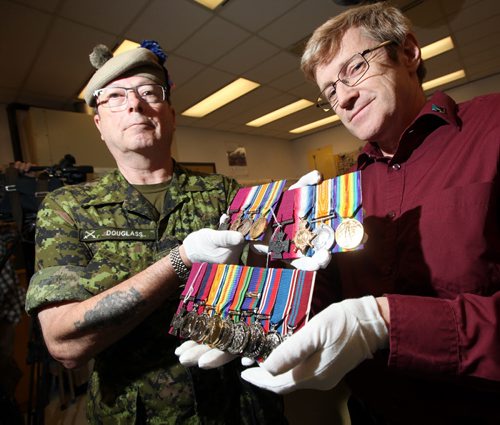 Major Paddy Douglass of the Queens Own Cameron Highlanders and Tony Glen, Director of Research and Collection at the Canadian War Museum unveil the three "Valor Road" medal sets including Victoria crosses to be displayed starting Wednesday at the Manitoba Museum. See release/story. August 5, 2014 - (Phil Hossack / Winnipeg Free Press) VALOUR ROAD VICTORIA CROSS MEDALS HAVE ARRIVED¤ IN WINNIPEG¤¤ Monday, August 4, 2014 ¤ WINNIPEG,Manitoba:¤The original Victoria Cross medals awarded almost 100 years ago to three Winnipeg soldiers who served in the First World War are now in Winnipeg¤and will be¤turned over to The Manitoba Museum by officials of the Canadian War Museum¤at a special ceremony¤this Wednesday, August 6. ¤ The public is¤welcome to attend the Opening Ceremonies for the¤ the Valour Road¤Victoria¤Cross Medal¤display that will get underway at¤1:30 P.M.¤in the Alloway Hall of The¤Manitoba¤Museum. ¤ The Victoria Crosses of Valour Road¤medals were awarded to Lieutenant Robert Shankland, Sergeant-Major Frederick William Hall, and Corporal Leo Clarke in the First World War. In that war, all three, in separate actions, distinguished themselves by their extreme bravery in fighting the enemy. ¤ At the time of their enlistment,¤the three had all resided in the same block of Pine Street in the west end of Winnipeg.¤In honour of the accomplishments of these¤Pine Street¤soldiers, a phenomena that was unique to¤Canada,¤Pine Street¤was renamed¤Valour Road¤in the 1920s.¤ ¤ The Victoria Crosses of Valour Road¤medals will be on public display at The Manitoba Museum until they are returned to their permanent home at the¤Canadian¤War¤Museum¤in¤Ottawa¤at the end of Remembrance Week, the 14th of November 2014. ¤ The project¤to bring The Victoria Crosses of Valour Road Exhibit to Winnipeg is a collaborative effort of The Royal Military Institute of Manitoba (RMIM),The Manitoba Museum and the Canadian War Museum and is¤supported by a grant from the Winnipeg Foundation.¤ ¤ ¤ --30 ¤ N