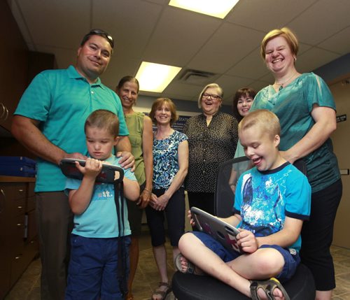 Philanthropy Page on Open Access Resource Centre (OARC), they provide communication devices to children and teens. From left, Mike Lisowski with son Isaac,6, with his Ipad, Lori Wiebe, executive director, Marnie Loewen, executive assistant, Penny McMillan, board pres., Jennifer Barthel, board member and Cheryl with son Joshua,9. The boy's  IPads have specialized apps provided through the Open Access Resource Centre (OARC). Kevin Rollason story. Wayne Glowacki/Winnipeg Free Press August 8 2014