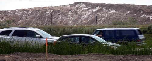 An 18meter high pile of melting snow still dwarfs cars moving along Kenaston near Lowson Friday afternoon. See story. August 8, 2014 - (Phil Hossack / Winnipeg Free Press)