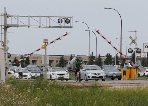 August 8, 2014 - 140808  -  Two men hold up stuck train track barriers to let traffic through on Route 90 Friday, August 8, 2014. John Woods / Winnipeg Free Press