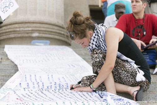 Calantha Jensen writes the names of those who have died in Gaza at the Legislative Building on Saturday. The list has been updated at each rally after more and more have been killed. Winnipeg has held four rallies for Gaza in the past three weeks. Sarah Taylor / Winnipeg Free Press August 9, 2014