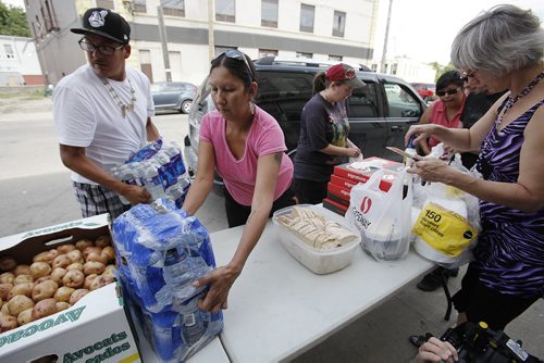 August 10, 2014 - 140810  -  Althea Guiboche (C foreground), The Bannock Lady, and her volunteers distribute food and clothing to local people on Dufferin at Main Sunday, August 10, 2014. Guiboche invited Gord Steeves and his wife Lorrie to volunteer after Lorrie's comments regarding homeless men in Winnipeg's downtown surfaced. The mayoral hopeful and his wife did not show up. John Woods / Winnipeg Free Press