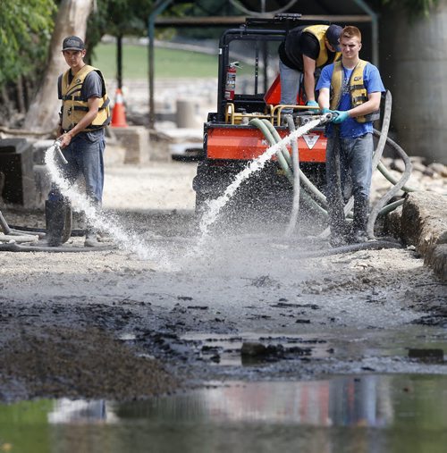 Stdup . Work crews begin to clean the walkway along the Assiniboine River from the forks of the Red River  to the Manitoba Legislature ,high and  heavy volumes of water  are beginning to lessen as the water level drops .   Aug 14 2014 / KEN GIGLIOTTI / WINNIPEG FREE PRESS