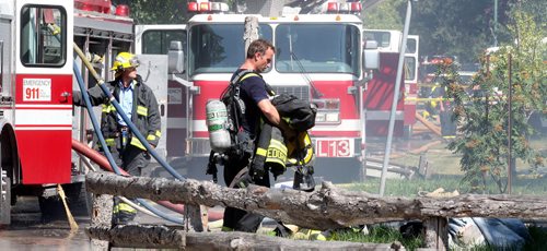 Firefighters and equipment line Nichols ave Friday afternoon as two homes went up in flames. Crews battled the fire as well as extreme heat. See story. August 15, 2014 - (Phil Hossack / Winnipeg Free Press)