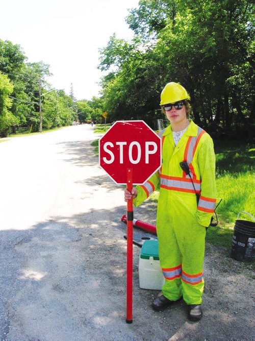 Canstar Community News Karsten Roche cautions oncoming traffic to detour becuase of darinage work occurring on Roblin Blvd. in the RM of Headingley.