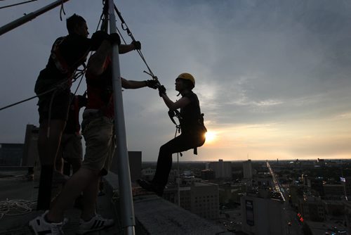 Sara Kenny with Vertical Adventures, steps onto the edge of the RBC Building, Wednesday evening just before rappelling down the 200 feet as part of the set up crew doing trial runs for tomorrows Drop Zone event which raises money for Easter Seals SMD Foundation.    Standup photo  Aug 20, 2014 Ruth Bonneville / Winnipeg Free Press