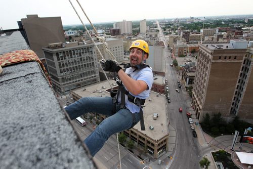 Steven Hill  with Vertical Adventures, reacts with excitement as he steps over the edge of the RBC Building Wednesday evening as he rappels down the side of the building,  as to the part of the set up crew doing trial runs for tomorrows Drop Zone event which raises money for Easter Seals SMD Foundation.    Standup photo  Aug 20, 2014 Ruth Bonneville / Winnipeg Free Press