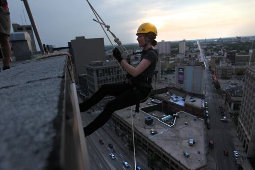 Sara Kenny with Vertical Adventures, steps over the edge of the RBC Building, Wednesday evening just before rappelling down the 200 feet as part of the set up crew doing trial runs for tomorrows Drop Zone event which raises money for Easter Seals SMD Foundation.    Standup photo  Aug 20, 2014 Ruth Bonneville / Winnipeg Free Press