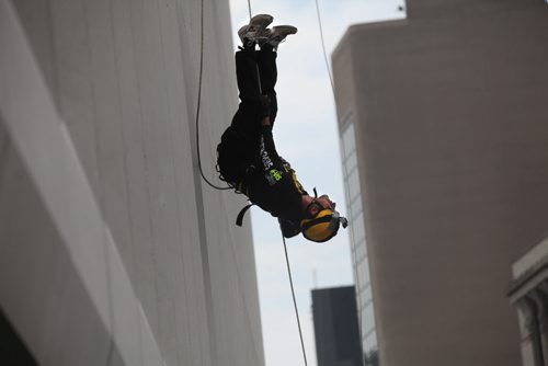 Warren Herntier flips upside down as he nears the bottom of the RBC building after rappelling 200 feet during the annual Easter Seals Drop Zone event.  Money raised in the the fundraising event  goes to Manitoban's living with disabilities. (SMD Foundation)  Standup photo  Aug 21, 2014 Ruth Bonneville / Winnipeg Free Press