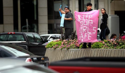 Protestors, many of them women and children stand on all four corners of Portage and Main street Friday afternoon during rush hour. Holding placcards protesting the Harper Governments decision not to hold an enquiry into the missing and murdered women. See release/story. August 22, 2014 - (Phil Hossack / Winnipeg Free Press)