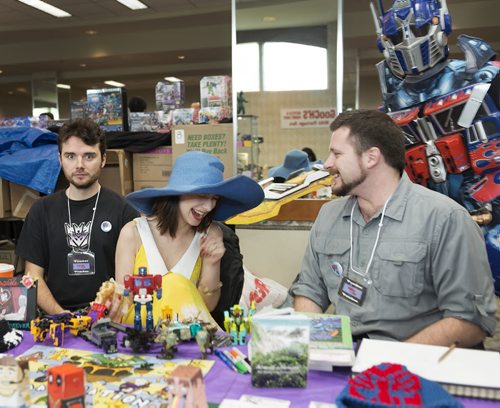 Optimus Prime photobombs William O'Donnell, Stacie Gagnon and Bart Rucinski at their Yak and Shadow vendor at Saturday's Transformers convention in the Clarion Hotel. Sarah Taylor / Winnipeg Free Press August 23, 2014