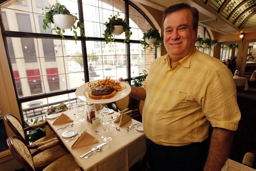 THIS CITY - Bailey's Restaurant & Lounge with  Leo Groumoutis (owner)with famed steak sandwich  : This is for a Sunday This City profile of Bailey's - a downtown institution since the early 70s. Owner Leo Groumoutis started there as a 13-year-old dishwasher and, a couple of decades later, ended up buying the place together with his brother George.  So shots of Leo - maybe holding up one of Bailey's signature dishes (they make a killer steak sandwich) - in one of the restaurant's dining rooms. We'll have room for five or six pics so also shots of the exterior - the lounge & pool table area, the library room - and if possible, there are a series of hidden tunnels in the basement that lead throughout the downtown - Leo used to play hide and seek down there as a kid, so that might be an interesting pic, too....story by Dave Sanderson .Aug 26 2014 / KEN GIGLIOTTI / WINNIPEG FREE PRESSin pic