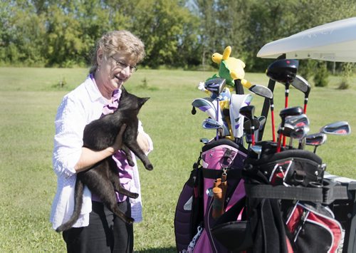 Juanita Cousins holds her cat Buddy who roams around the golf course she and her husband Jerry have built on their 65 acre property in Whitemouth.  Sarah Taylor / Winnipeg Free Press August 27, 2014 Bill Redekop story