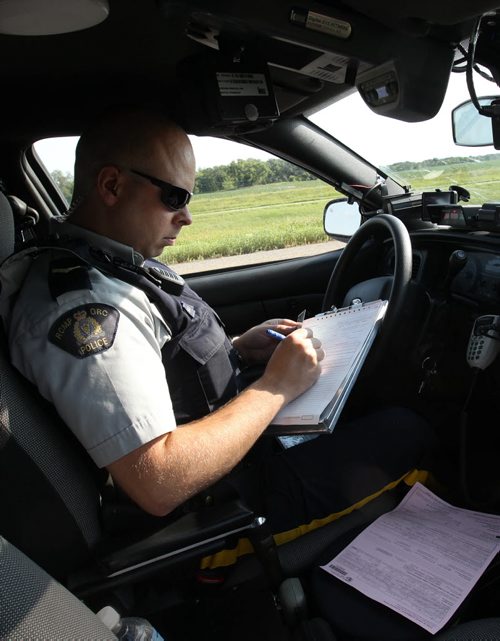 RCMP CPL Mark Hume writes ticket  during traffic enforcement on Hyw #1 near Portage La Prairie  See Mary Agnes Welch  story- Aug 08, 2014   (JOE BRYKSA / WINNIPEG FREE PRESS)