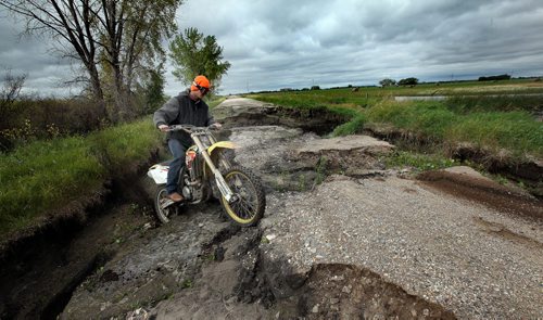 Water Woes.....A dirt bike rider negotiates a retreat from a creek crossing that washed out a municipal road near Pierson Mb. Unusual rainfall patterns and uncontrolled drainage has left most fields in the area unproductive this season and some for multiple seasons. Roads and bridges have also been washed out. See Larry Kusch story. August 25, 2014 - (Phil Hossack / Winnipeg Free Press)