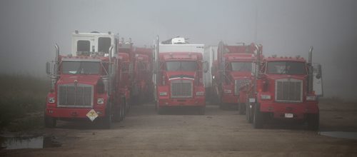 Oil Industry service trucks sit idle in an early morning mist in Melita Mb. Soggy roads and washed out bridges plague oil production as well as agriculture. Unusual rain patterns and drainage issues from Saskatchewan and Manitoba farmers have created agricultural and Municipal headaches.  See Larry Kusch story. August 26, 2014 - (Phil Hossack / Winnipeg Free Press)