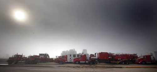 Oil Industry service trucks sit idle in an early morning mist in Melita Mb. Soggy roads and washed out bridges plague oil production as well as agriculture. Unusual rain patterns and drainage issues from Saskatchewan and Manitoba farmers have created agricultural and Municipal headaches.  See Larry Kusch story. August 26, 2014 - (Phil Hossack / Winnipeg Free Press)