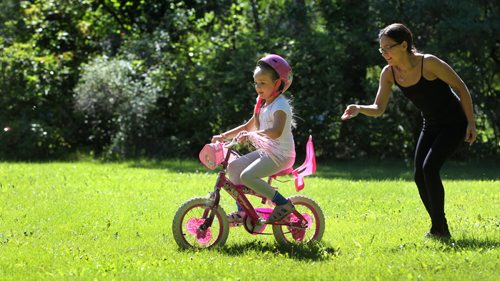 Six-year-old Amara Dumont, with the help of her mom Jamie, learns to ride her bike for the 1st time without training wheels in a park off Lanark Street Saturday.   Standup photo     Aug 30, 2014 Ruth Bonneville / Winnipeg Free Press   Ruth Bonnevilles