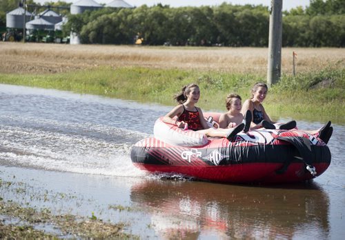 Siblings Anna, 14, Andrew, 11, and Samantha Schmidt, 16, tube in the ditch next to their house in Niverville on Saturday after yesterday's heavy downpour. Sarah Taylor / Winnipeg Free Press August 30, 2014