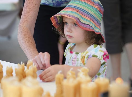 Three-year-old Avalyn Stovart checks out candles made of natural beeswax by artist Gwen Fehr with Joan's Beeswax Candles while attending the  Forks Saturday during the PRAIRIE BARGE FESTIVAL - Manitoba and Saskatchewan artists team up for three days of music, art and culture showcasing the diverse talent of the Prairies.    Aug 30, 2014 Ruth Bonneville / Winnipeg Free Press   Ruth Bonnevilles   \