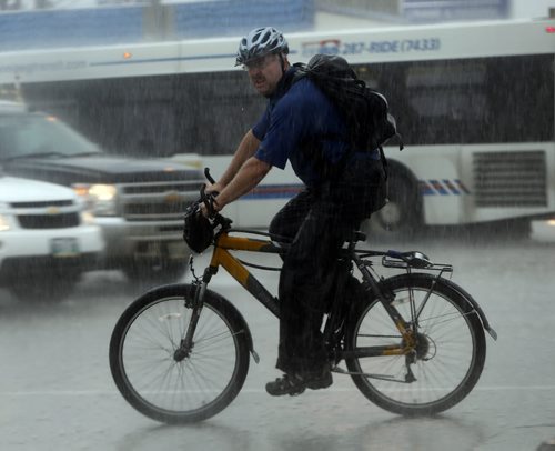 Stdup Heavy rain arrives as a is  cyclist caught in the heavy downpour and traffic  on McPhillips St. and Logan Ave SEPT  4 2014 / KEN GIGLIOTTI / WINNIPEG FREE PRESS