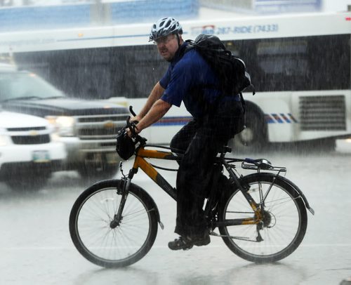 Stdup Heavy rain arrives as a is  cyclist caught in the heavy downpour and traffic  on McPhillips St. and Logan Ave SEPT  4 2014 / KEN GIGLIOTTI / WINNIPEG FREE PRESS